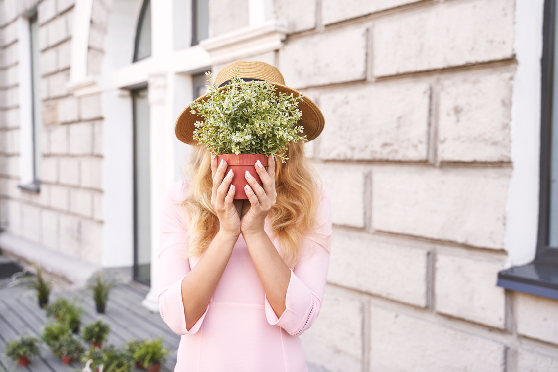 Young Woman Hiding face with Potted Plant